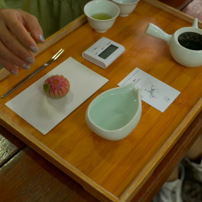 Top-down bamboo tea tray with a pink chrysanthemum wagashi and matcha