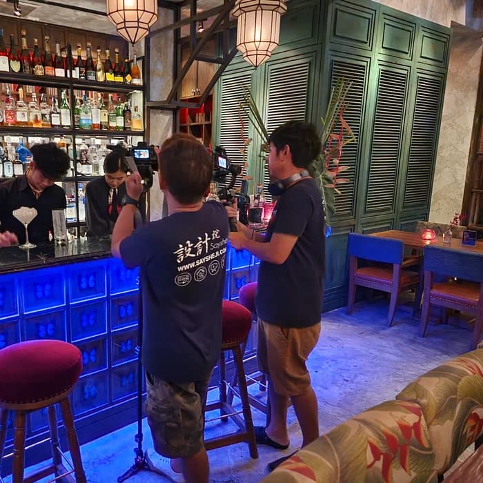 Bartender straining a cocktail behind a blue-lit speakeasy bar