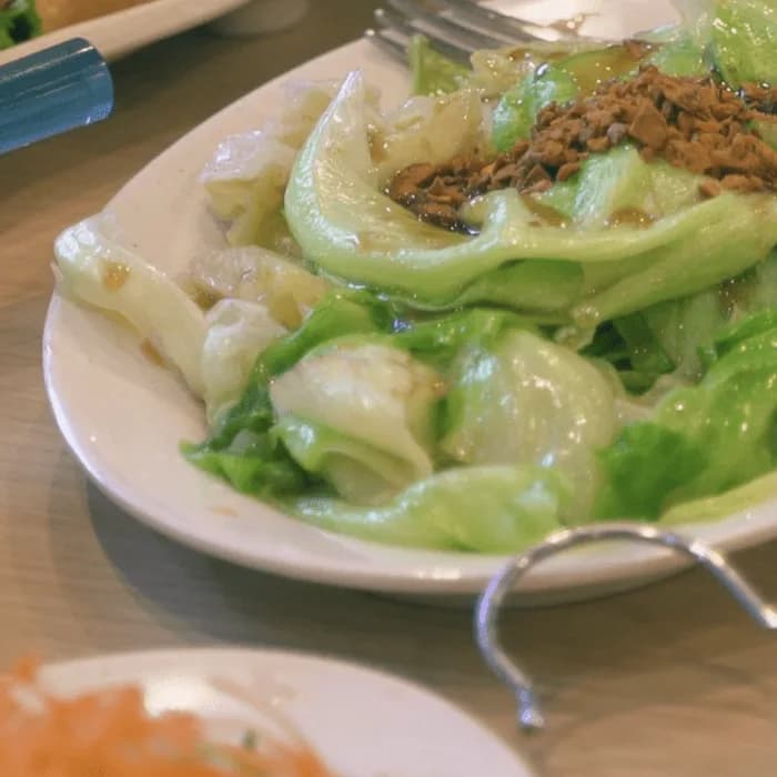 Close-up of dressed butter-lettuce salad topped with crisp minced pork