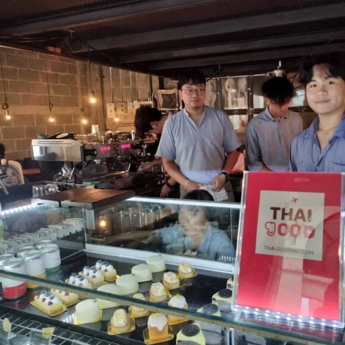 Three baristas behind a bakery pastry case with the partner card on the counter